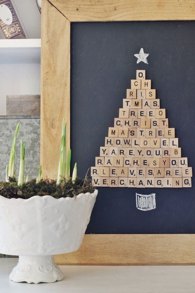 a wooden scrabble christmas tree sitting next to a potted succulent