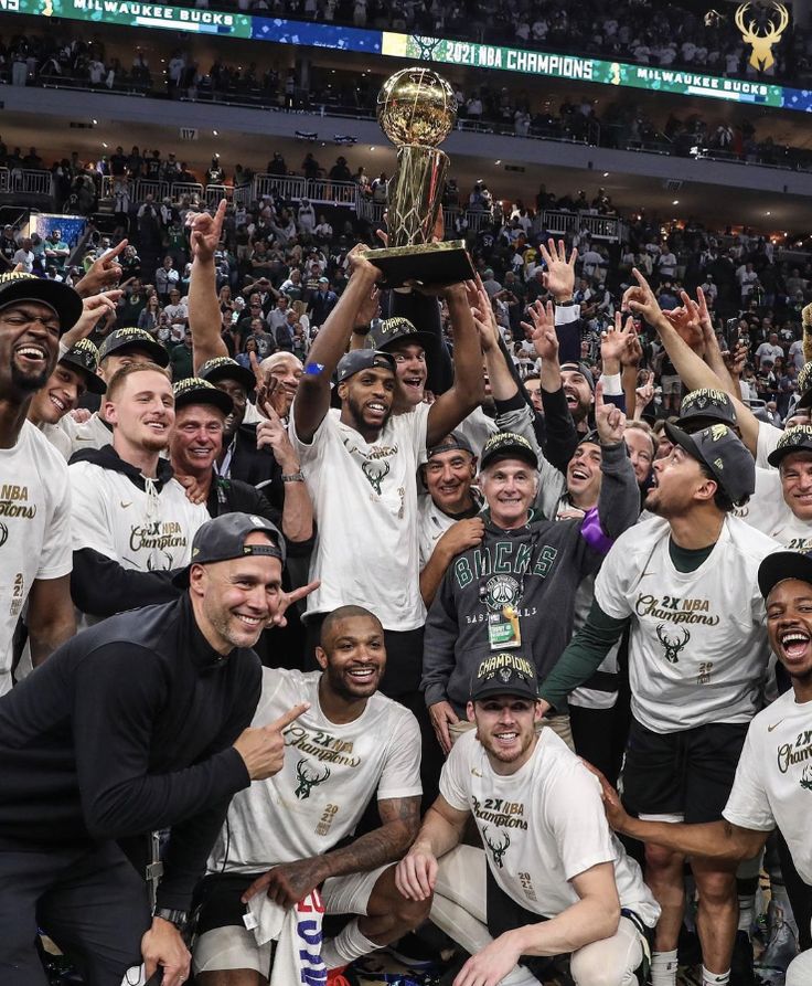 a group of men standing next to each other on top of a basketball court holding up a trophy