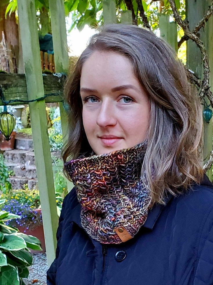 a woman standing in front of a tree wearing a scarf