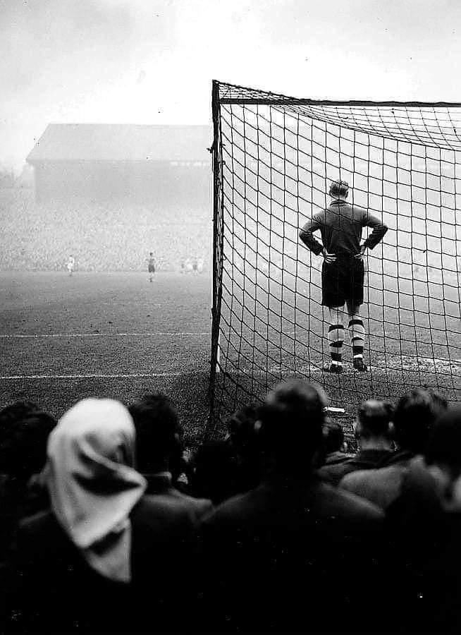 a man standing in front of a soccer goal with his hands on his hips as people watch