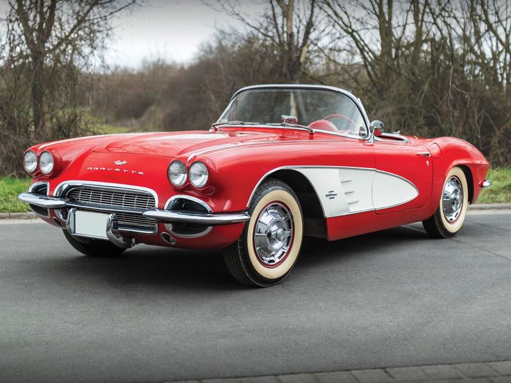 an old red and white car is parked on the street