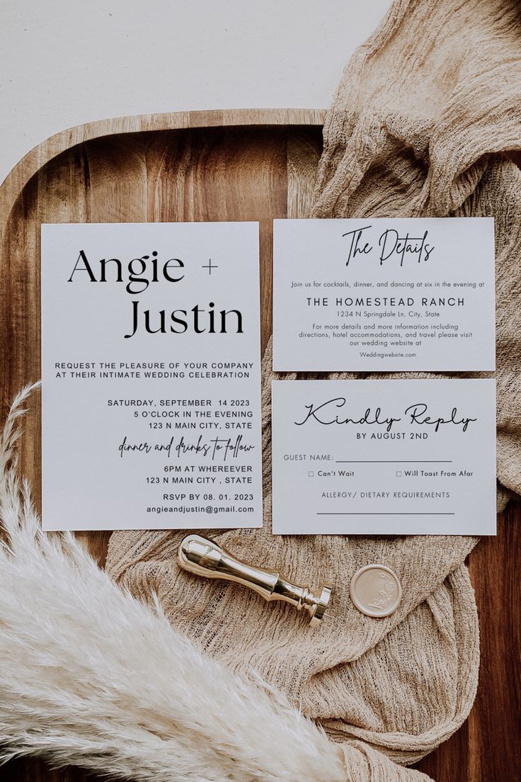 the wedding stationery is laid out on a wooden tray