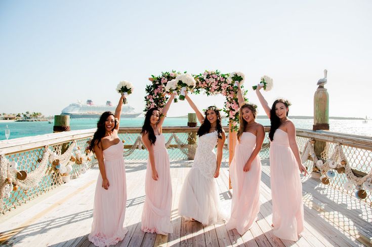 four bridesmaids pose on a pier with their bouquets in front of them