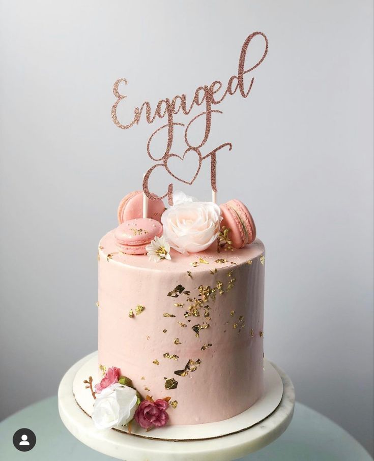 a pink cake with gold sprinkles and flowers on top that says engaged