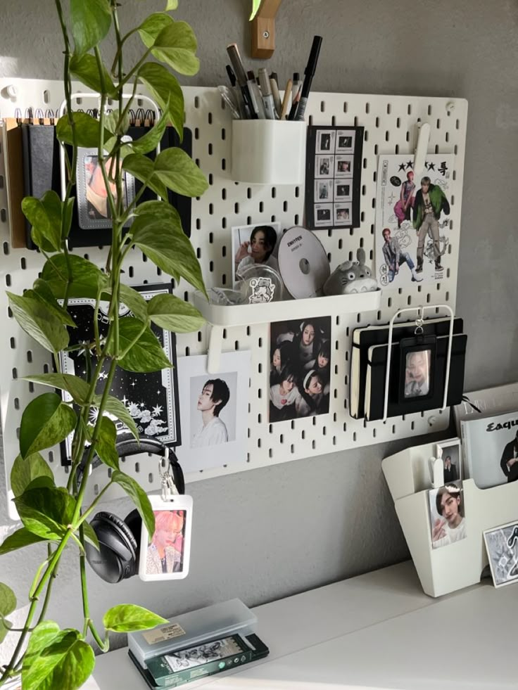 a white desk topped with lots of pictures next to a potted plant and phone