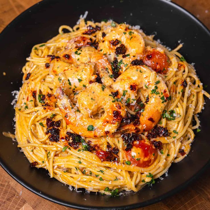 pasta with shrimp, tomatoes and parmesan cheese on a black plate