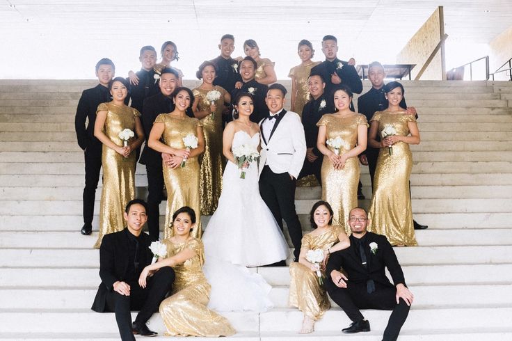 a group of people posing for a photo in front of some stairs with gold dresses