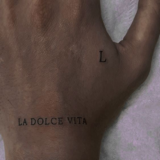 a hand with the word la dolce vita tattooed on it's left side