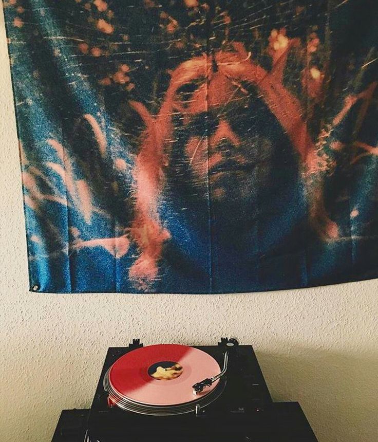 a record player sitting on top of a turntable in front of a wall tapestry