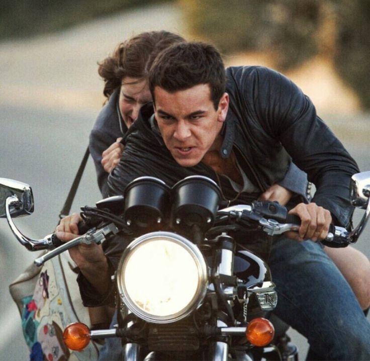 a man and woman riding on the back of a motorcycle