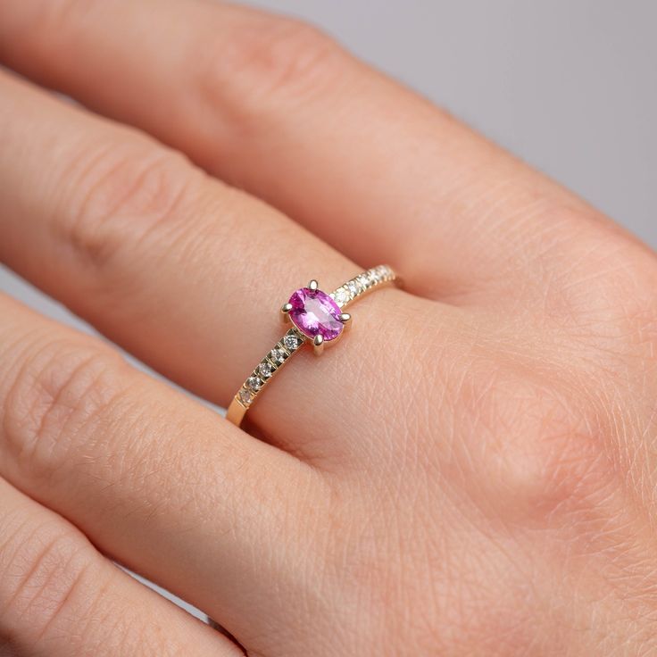 An engagement ring made of 14K solid gold with a natural vivid pink Ceylon sapphire unheated and untreated oval cut on top, with side diamonds on the band. It has a comfort fit, so you can wear it everyday.  100% handcrafted. D E T A I L S ● Metal: 14K solid gold ● Gemstone: Pink Sapphire, unheated and untreated oval cut, Diamonds  ● Gemstone's weight: Sapphire 1.02 ct, Diamonds 0.08 ct, color G, clarity SI H O W ∙ T O ∙ O R D E R Choose from the drop-down menus of the available options (Ring size) and leave us a note for any special requirements. G I F T S All our pieces are delivered beautifully packaged and gift ready. P R O D U C T I O N ∙ T I M E * S H I P P I N G  Please keep in mind that each item is handcrafted, and we need 5 days at least for its production. If you need your order Pink Ruby Promise Ring With Rose Cut Diamonds, Pink Oval Birthstone Ring With Prong Setting, Oval Pink Gold Ring With Brilliant Cut, Formal Pink Oval Birthstone Ring, Pink Oval Birthstone Promise Ring, Oval Pink Ruby Ring As Gift, Oval Pink Sapphire Ring For Anniversary, 14k Pink Gold Oval Ring, Oval Pink Sapphire Anniversary Ring