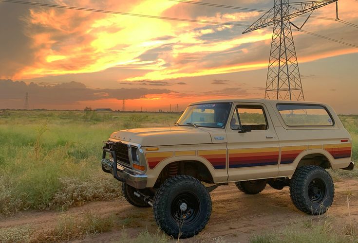 a truck is parked on a dirt road in front of an electric tower at sunset