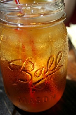 a mason jar filled with lemonade sitting on top of a wooden table next to a straw