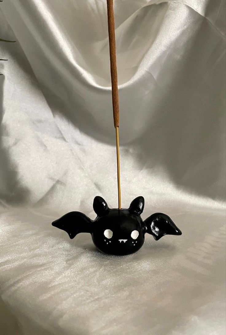 a small black bat shaped object with a wooden stick sticking out of it's mouth