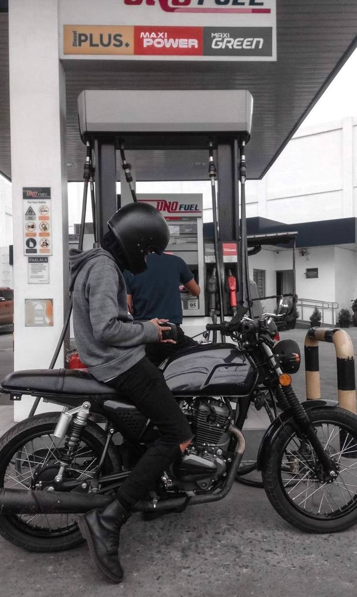 a man sitting on a motorcycle at a gas station