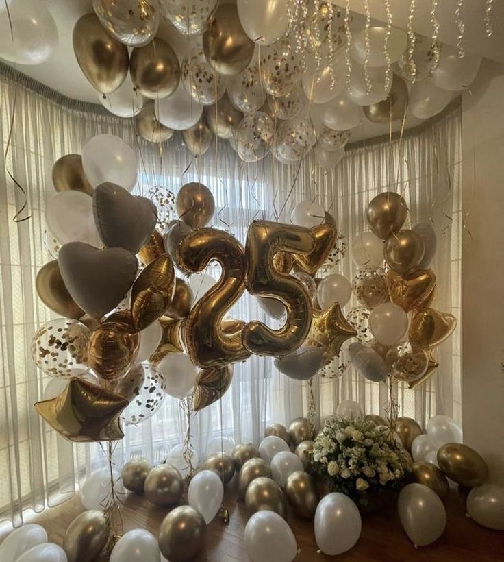 balloons and streamers are hanging from the ceiling in front of a large number twenty five balloon