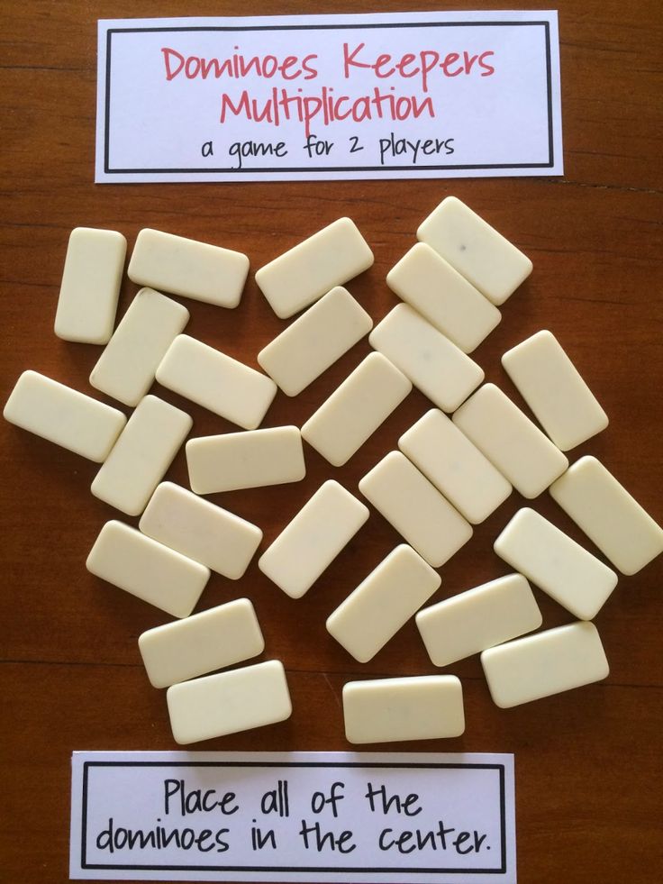 pieces of white dominos sitting on top of a wooden table next to a sign