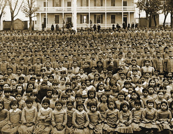 an old black and white photo of people in front of a large house with many windows