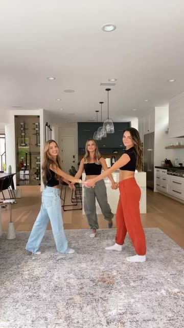 three young women are dancing in the living room