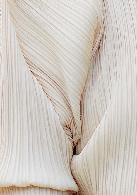 the back of a woman's white dress with pleated details