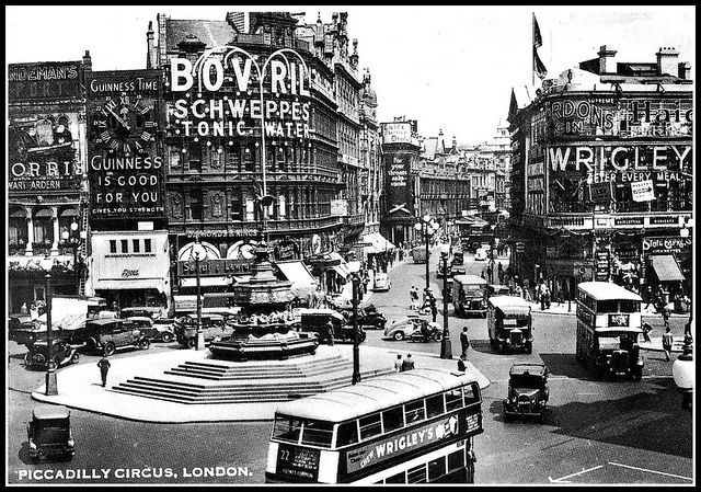 an old black and white photo of a busy city street with double decker busses