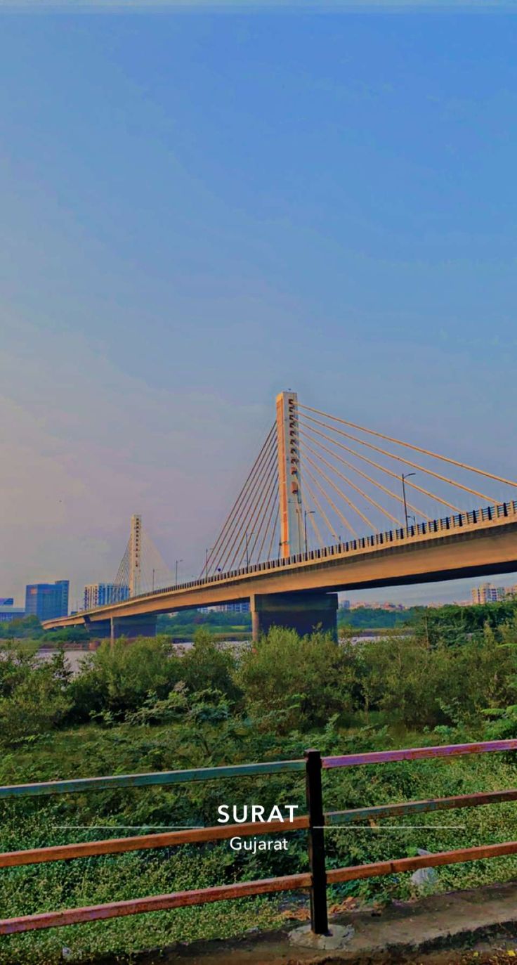 there is a sign that says surat on it in front of the water and bridge