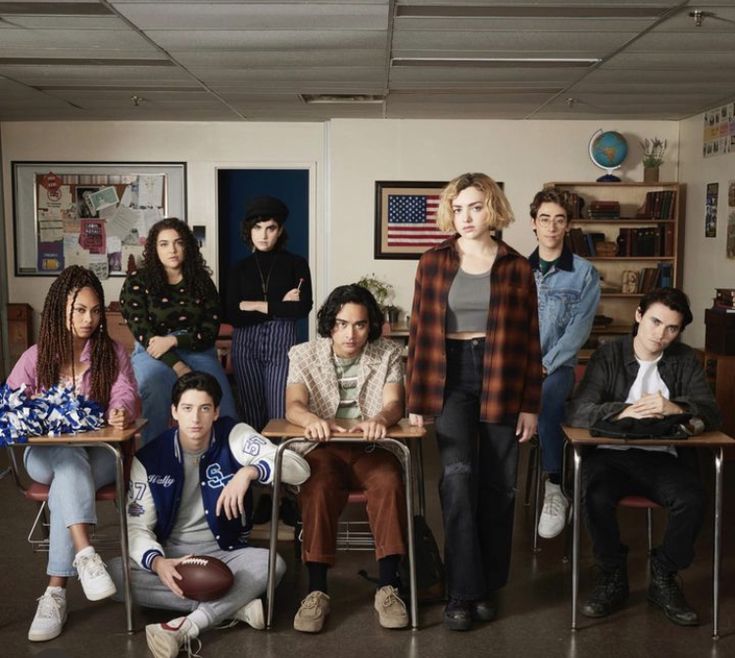 a group of people standing and sitting in front of desks