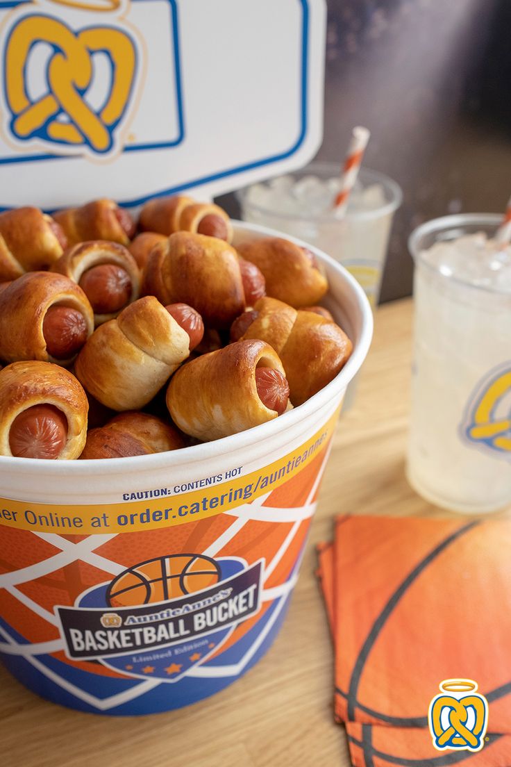 a bucket filled with hot dogs sitting on top of a table