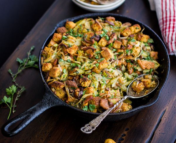 a skillet filled with stuffing on top of a wooden table next to other dishes