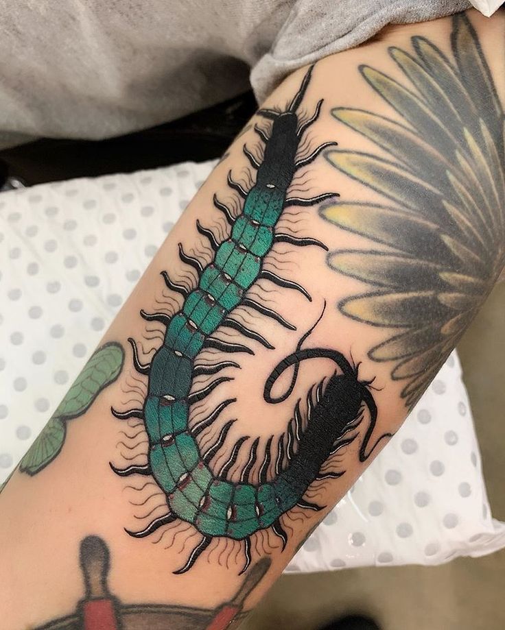 a tattoo with a green and black caterpillar on it's left arm