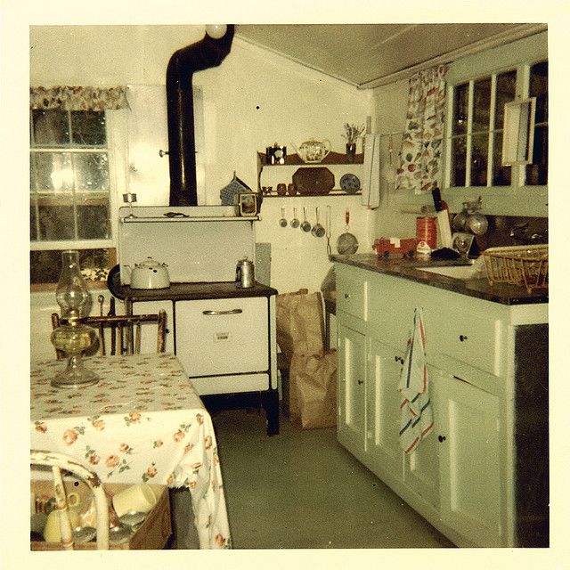 an old fashioned kitchen with white appliances and floral table cloths on the counter top