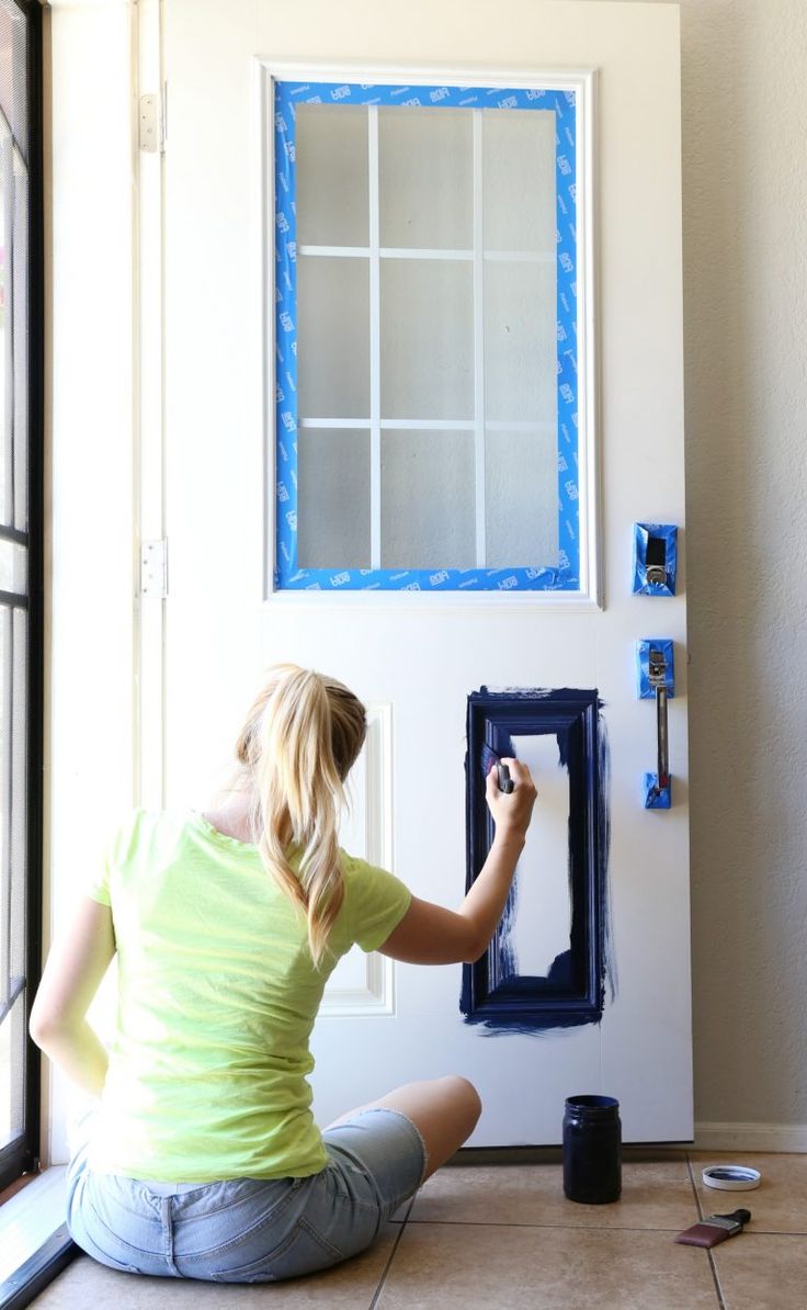 a woman is sitting on the floor and painting a wall with blue trim around it