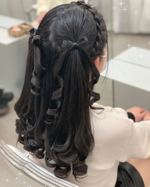 a woman with long black hair sitting in front of a mirror