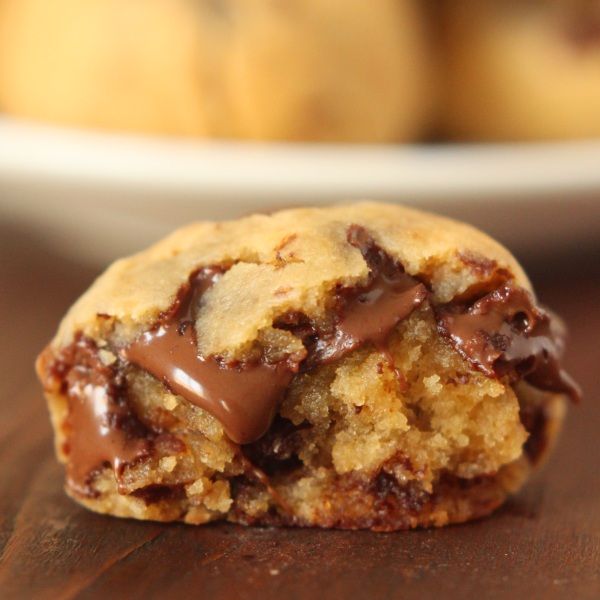 a chocolate chip cookie on a table with bananas in the background