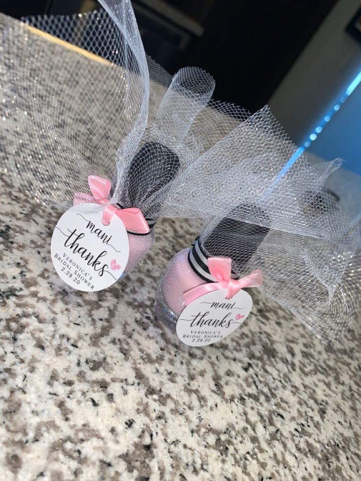 two pink and black cookies with bows on them sitting on top of a marble counter