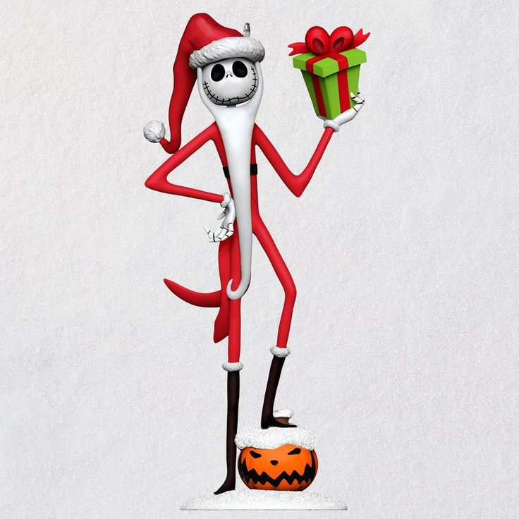 a christmas ornament with a santa clause hat holding a gift box and standing on a pumpkin