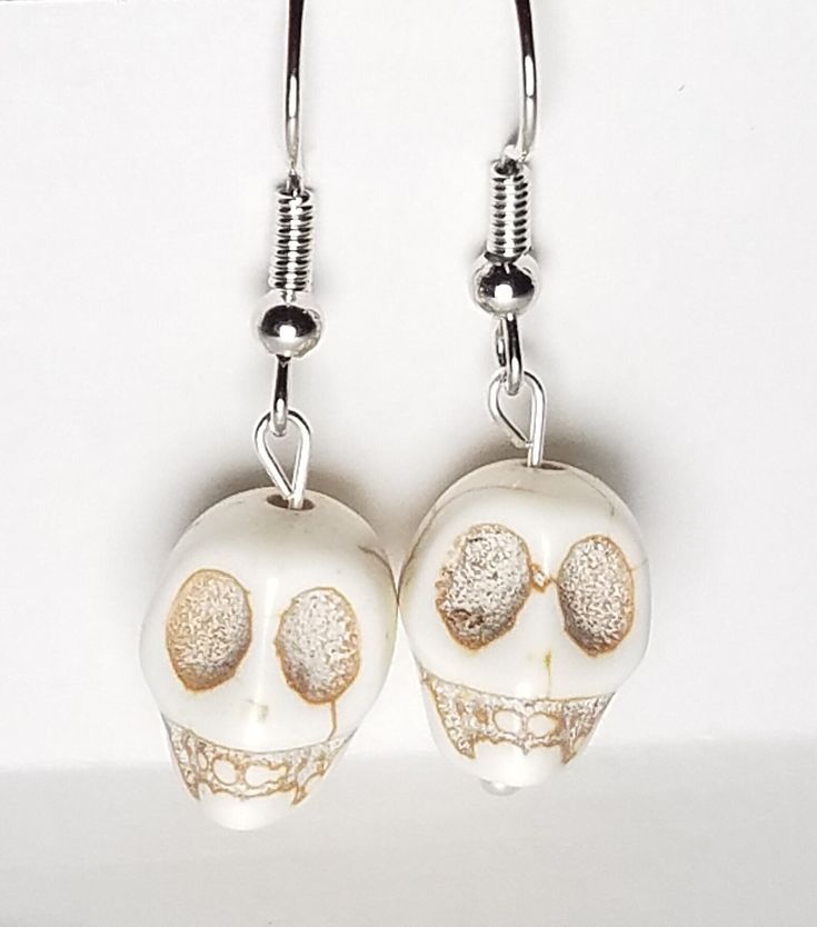 A pair of earrings made using skull beads. Perfect for Halloween! Each earring measures approximately 1.5 inches from top of earring wire to bottom of beads. Each pair comes with 2 earring backs. Bone Color Dangle Earrings With Ear Wire, Nickel-free Bone Dangle Earrings, Nickel-free Bone-colored Dangle Earrings, Nickel Free Bone Color Dangle Earrings, Halloween Skull Jewelry With Ear Wire, Gold Skull Earrings Nickel Free, White Skull Jewelry For Halloween, Halloween Skull Jewelry In White, White Skull-shaped Halloween Jewelry