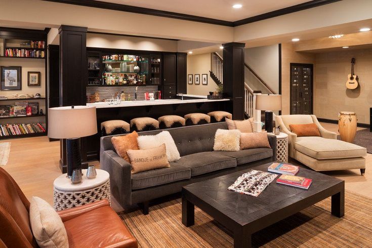 a living room filled with furniture and a bar in the back drop off wall behind it