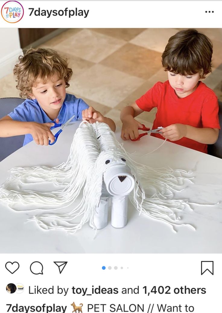 two young boys are working on a paper dog sculpture at a table in the living room