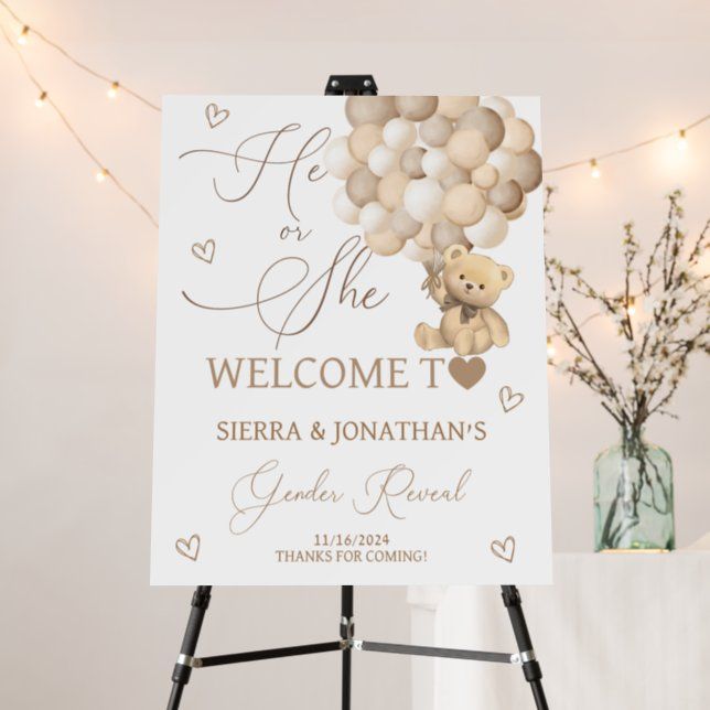 a welcome sign with balloons and a teddy bear in the center is on an easel