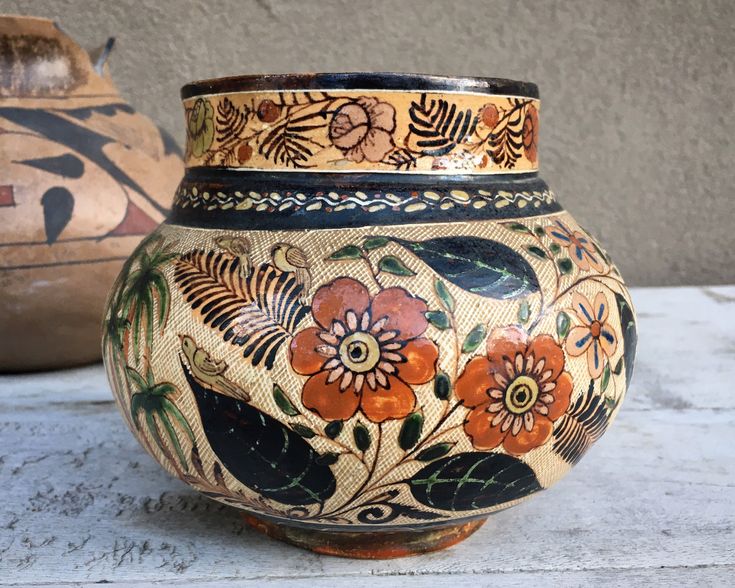 two vases sitting on top of a table next to each other with flowers painted on them