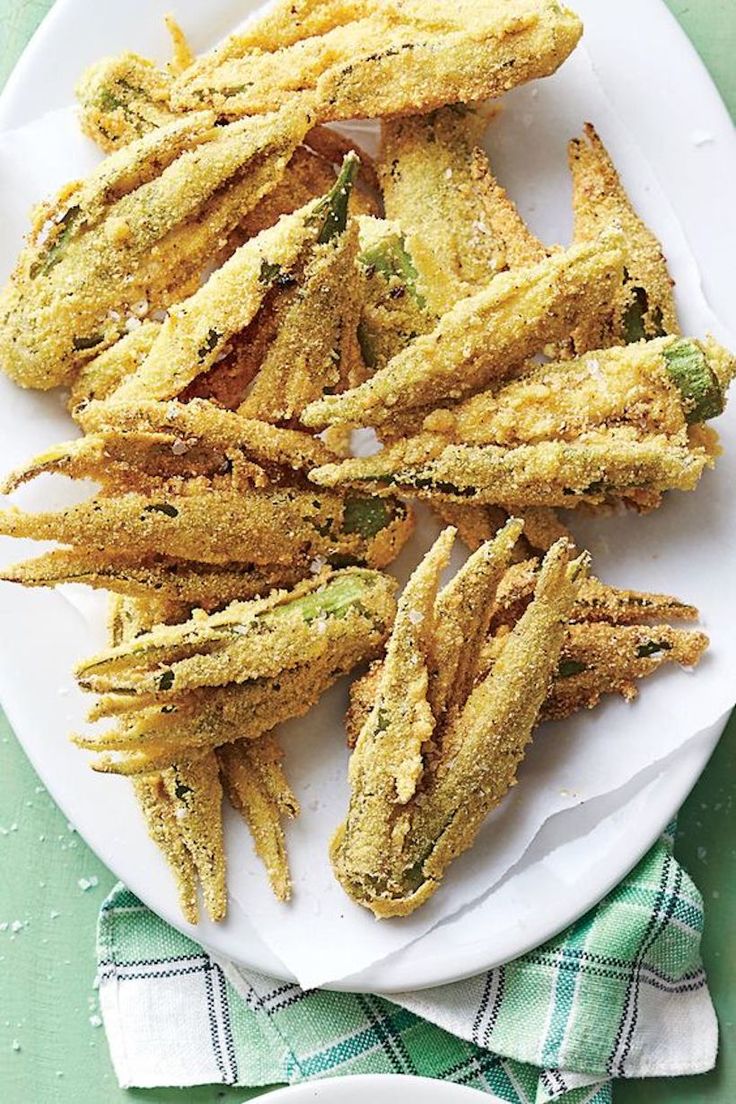 some fried food on a white plate next to a green and blue napkin with a fork