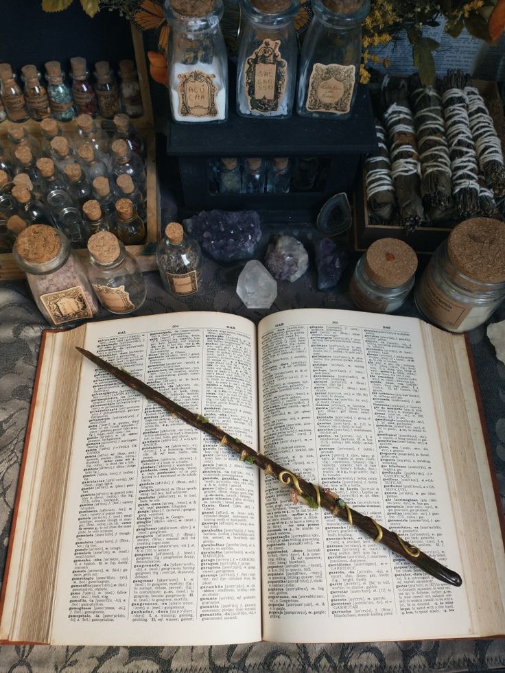 an open book sitting on top of a table filled with harry potter's wands