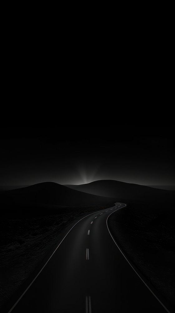 an empty road in the middle of nowhere at night with light coming from behind it