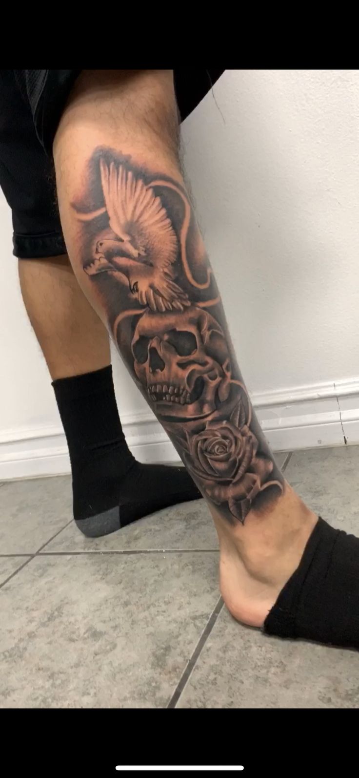 a man's leg with a skull and rose tattoo on the left side of his leg