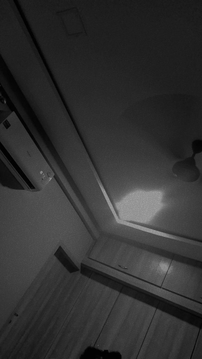 a black and white photo of a room with a fan on the ceiling, light coming in