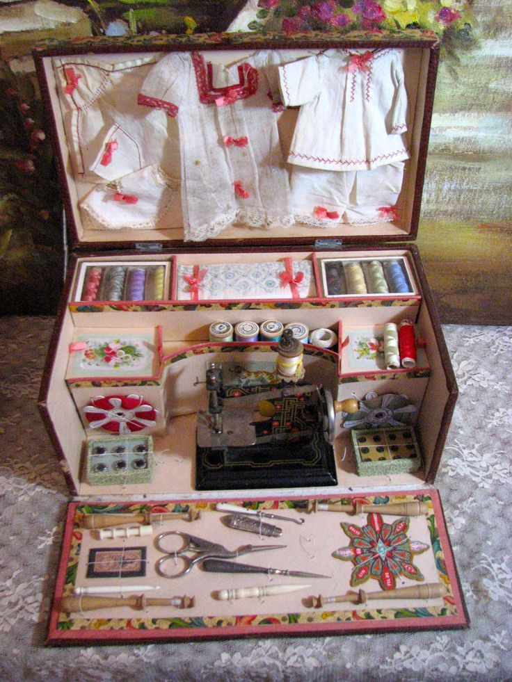 an open suitcase with sewing supplies in it on a tablecloth covered surface and flowers