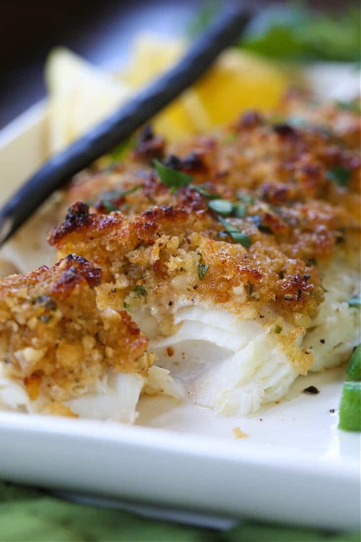 a white plate topped with fish covered in sauce and garnished with green onions