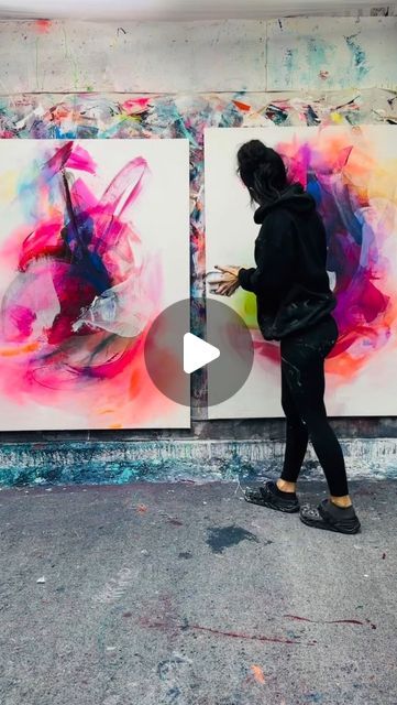 a woman walking past two paintings in an art studio