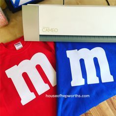 two t - shirts with m and m on them are sitting next to a computer